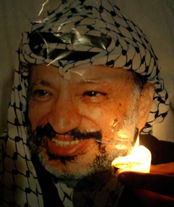 A Palestinian man holds up a candle in front of a poster of Palestinian President Yasser Arafat during a demonstration in the West Bank city of Ramallah on November 8, 2004. Palestinian leaders headed to Paris on Monday to see critically ill President Yasser Arafat at a French military hospital despite a scathing attack by his wife who accused them of plotting to "bury him alive." [Reuters]