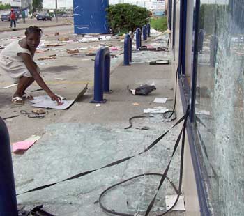 A woman bends over debris outside a looted shop in the Ivory Coast capital of Abidjan following protests, November 9, 2004. At least five people were killed in a fourth day of mob violence in Ivory Coast on Tuesday and protesters accused French troops of opening fire on them. Demonstrators said French troops had shot at them from a hotel in an upmarket district of the country's main city Abidjan, while the French military declined immediate comment. [Reuters]