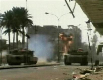 A tank fires a round into a building in this TV image as U.S. troops, along with Iraqi forces, powered their way into the center of the insurgent stronghold of Fallujah, Iraq, on Tuesday, Nov. 9, 2004, overwhelming small bands of guerrillas with massive force, searching homes along the city's deserted, narrow passageways and using loudspeakers to try to goad militants onto the streets. [AP]
