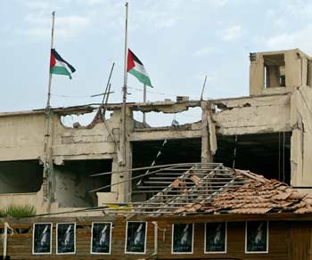 Palestinian flags fly half-staff over the damaged headquarters of President Yasser Arafat in Gaza, November 11,2004. [Reuters]