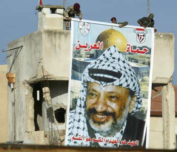 Palestinian security guards install a giant poster of the late Palestinian President Yasser Arafat at the "Muqata" compound where he is expected to be buried in the West Bank city of Ramallah November 11, 2004. [Reuters]