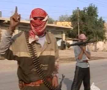 A masked gunman speaks as insurgents clashed with Iraqi police and U.S. soldiers in Buhriz, 60 km (37.3 miles) northeast of Baghdad, November 15, 2004. Gunmen stormed the police station in the the town of Buhriz on Monday using machine guns and rocket-propelled grenades, police said. A gunbattle ensued and four police cars were burned, police said. [Reuters]