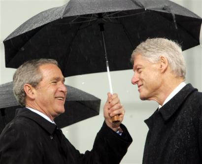 Former President Bill Clinton (right) and President George Bush pass on the stage during dedication ceremonies for the William J. Clinton Presidential Center, Thursday, Nov. 18, 2004, in Little Rock, Ark. [AP]