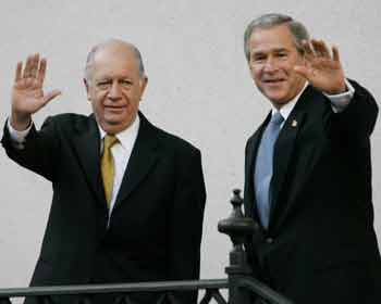 U.S. President George W. Bush (R) stops to wave while being escorted by Chilean President Ricardo Lagos into La Moneda Palace, at the beginning of a state visit after the closing of the annual meeting of the Asia Pacific Economic Cooperation (APEC) in Santiago, November 21, 2004. [Reuters] 