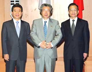 South Korea's President Roh Moo-hyun (L), Japan's Prime Minister Junichiro Koizumi (C) and China's Premier Wen Jiabao lock hands for a photo before holding a trilateral meeting at the10th Association of Southeast Asian Nations (ASEAN) Summit in Vientiane on November 29, 2004.