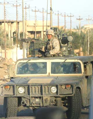 A U.S. Marine stands watch as troops continue a house-to-house search for weapons and insurgents in the war-torn city of Falluja November 28, 2004. U.S. Marines said they killed several insurgents and took 32 suspects in a series of actions south of Baghdad on Sunday that included a high-speed riverborne raid on suspected weapons dumps on the Euphrates. Picture taken November 28, 2004. [Reuters]