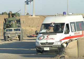 A Red Crescent ambulance passes a U.S. Marine vehicle at a traffic checkpoint in the war-torn city of Falluja November 28, 2004. [Reuters]