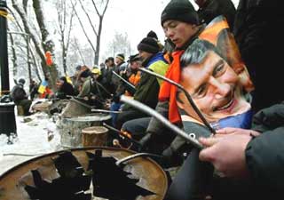 Supporters of Ukrainian opposition candidate Viktor Yushchenko beat drums made from empty barrels, in Kiev, Tuesday, Nov. 30, 2004, with Yushchenko's portrait at right. Yushchenko, who claims he was cheated out of victory in the Nov. 21 run-off election, is demanding a new vote. Hundreds of thousands of demonstrators have jammed downtown Kiev for a week to support him.(A