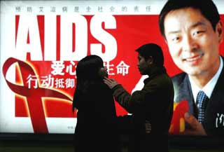 A Chinese couple wait for a ride in front of an AIDS awareness poster at a subway station in Beijing marking World AIDS Day December 1, 2004. China, criticized for its slow initial response to HIV/AIDS put on a public display of commitment to fighting a disease which the United Nations fears could infect 10 million Chinese by 2010. 