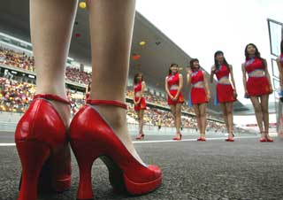 Chinese grid girls make way for Formula One drivers at the inaugural Chinese Grand Prix at the Shanghai Circuit in this September 26, 2004 file photo. The world's most populous country is waking up to Formula One and the money-burning sport is eager to tap into it. While some Chinese companies now seem ready to embrace the sport after initial wariness, teams and foreign multi-nationals are clear about Formula One's usefulness as a platform to promote brand awareness. 