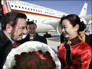 German Chancellor Gerhard Schroeder (L) gets roses from a flower girl at Beijing airport. Schroeder arrived in China for meetings with President Hu Jintao and Prime Minister Wen Jiabao to oversee a raft of deals, including an expected order by Beijing for Airbus jets, and to discuss the EU arms embargo against the communist country(AFP
