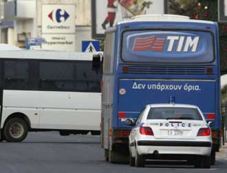 A police car is seen behind a hijacked bus on a street some 30 kilometres north of Athens December 15, 2004. Greek police forces surrounded the bus after two armed men hijacked it early Wednesday morning with 26 passengers on board on its way from northern Athens suburbs to the Greek capital.