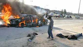 An Iraqi boy looks at the bodies of men laying next to their burning car after they were attacked by gunmen in the northern Iraq city of Mosul December 17, 2004. Insurgents attacked the car carrying at least three Westerners, killing them and their Iraqi driver, and chopping off the head of one victim, local witnesses said. [Reuters] 