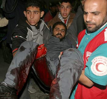 A wounded Palestinian man is carried to hospital after he was injured during an Israeli raid at the Khan Younis refugee camp in southern Gaza Strip, December 22, 2004. Two Palestinian gunmen were killed in exchanges of fire during an Israeli raid on the Gaza Strip refugee camp of Khan Younis, where the army said it was trying to stop mortar attacks on nearby Jewish settlements. [Reuters]