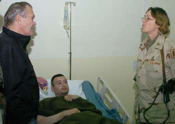 U.S. Secretary of Defense Donald Rumsfeld presents a purple heart medal to a soldier who was wounded on Tuesday in an attack on a U.S. military installation in Mosul, December 24, 2004. [Reuters]