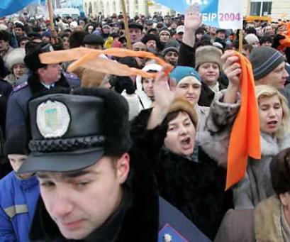 A police officer watches as supporters of Ukrainian opposition leader Viktor Yushchenko wave orange campaign ribbons amid supporters of Prime Minister Viktor Yanukovich, who hold up white and blue banners, during a joint meeting in the village of Berehove in Ukraine, December 24, 2004. Yanukovich traveled to the region to meet with voters on the last day of campaigning before Sunday's rerun of Ukraine's rigged presidential election. [Reuters] 