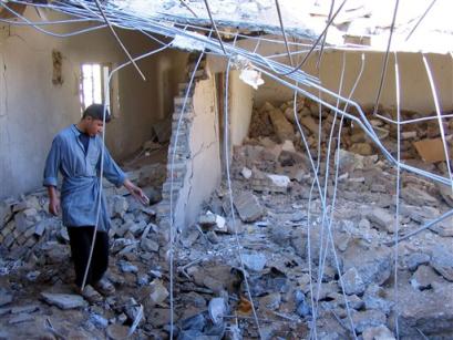 A man checks a destroyed police station 20 kilometers (12 miles) south of Tikrit, Iraq, Tuesday Dec. 28, 2004. Twelve policemen died when gunmen attacked the station. [AP]
