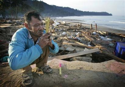 Kusol Wetchakul offers prayers for the soul of his sister Wednesday, Dec. 29, 2004, at dawn along the beach near Khao Lak, Thailand. Wetchakul's sister was swept out to sea and believed drowned as she sold goods to tourists on the popular tourist beach just north of Phuket. Thailand continues to struggle with the massive disaster as more than 1,500 have been killed by the tsunami wave that struck last Sunday. [AP]