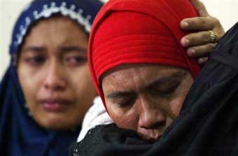 Acehnese women weep over the loss of relatives after tidal waves hit following Sunday's earthquake, at the airport in Banda Aceh, Aceh province, Indonesia, Tuesday, Dec. 28, 2004. At the northern tip of Indonesia's Sumatra island, emergency workers find that 10,000 people were killed in a single town near the epicenter of Sunday's earthquake, and survivors report entire towns inundated by water and starving families surviving on coconuts. (A