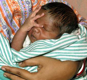 Six-day-old Tsunami Roy, sleeps in his mother's arms inside a relief camp at Port Blair January 1, 2005. Tsunami was born three weeks ahead of time, on a rocky slope where his parents had fled from the killer waves that lashed Hut Bay on India's remote Little Andaman island. 