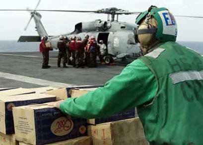 Boxes of bottled water are seen on the flight deck of the USS Abraham Lincoln before being flown into the tsunami stricken areas of Indonesia, January 4, 2004. U.S. military crews are launching more than 100 helicopter flights a day ferrying food, water and medicine to tsunami victims, a task they say is far more satisfactory than the Iraq war that seems only to destroy. [Reuters]