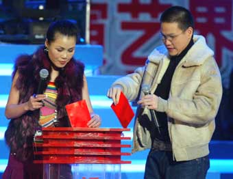 Mainland pop singer Tian Zheng (L) and Hong Kong performer William So make their donations for the Indian Ocean tsunami victims at a charity performance in Beijing January 6, 2005. [newsphoto]