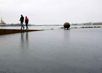 People walk along a flooded section of the Neva river embankment in St.Petersburg, January 9, 2005. [Reuters]
