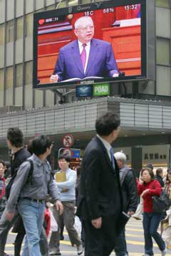 Hong Kong residents on a downtown street catch a glimpse of HK Chief Executive Tung Chee-hwa on a giant TV screen as he made his 2005 policy address to the Legislative Council January 12, 2005. [newsphoto]