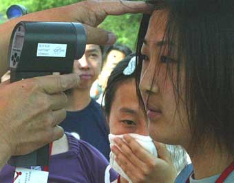 A student receives a temperature check through an auto-thermometer before attending the national college entrance examination in Beijing in this June 7, 2003 file photo. China was hit by an outbreak of SARS between March and July that year. [newsphoto]