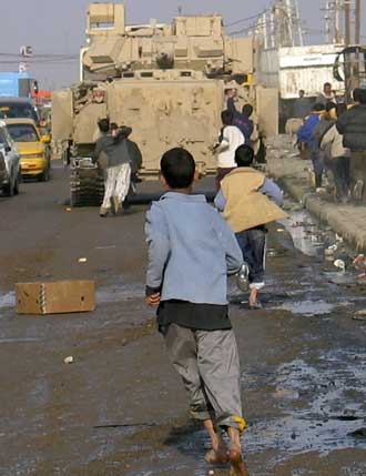 Iraqi children throw rocks at a U.S. Army armoured vehicle in the Shi'ite neighbourhood of Sadr City in Baghdad January 16, 2005. Iraq's elections will be legitimate if roughly half the Sunni Arab minority votes despite threats of violence, a leading politician in the Shi'ite alliance expected to dominate the polls said on Saturday.