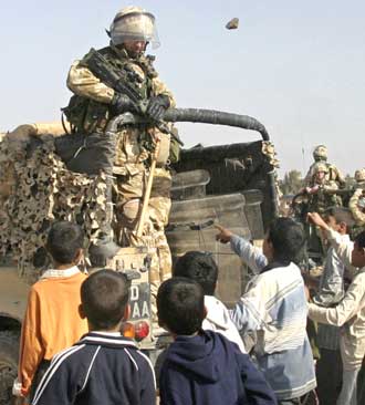 A rock thrown by a local youth flies past the head of a British soldier as the troops depart following a raid near the southern Iraq city of Basra January 16, 2005. Unable to deliver on its lofty goal of bringing democracy to Iraq through the January 30 elections, the U.S. administration is pressing a damage-control campaign to lower expectations for the vote. [Reuters]