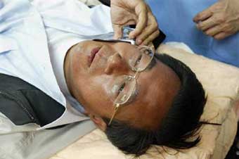 Chen Shui-bian seen talking on his mobile phone while doctors treat a gunshot wound on his stomach at Chi Mei Hospital after an assassination attempt during an election campaign rally in Tainan, southern Taiwan on the eve of a presidential election in this March 19, 2004 file photo. The opposition-led inquiry has found that Chen faked the attack to swing the election. [Reuters]