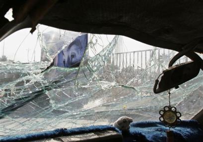 An elections poster of Iraqi Interim Prime Minister Ayad Allawi is seen through a windshield of a car damaged in an explosion outside a police station in Baghdad, Wednesday, Jan. 19, 2005. A car bomb exploded near the police station half hour after the blast near the Australian Embassy in central Baghdad on Wednesday killed two people. [AP]