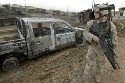 A U.S. Army 1st Battalion, 24th Infantry soldier stands near an Iraqi National Guard truck damaged in an engagement between U.S. forces and insurgents, in which five insurgents were killed in Mosul, Iraq, Thursday, Jan. 20, 2005. U.S. forces have intensified operations in Iraq's third largest city in a race to make it safe enough for voters to cast ballots in the country's Jan. 30 parliamentary and regional elections. [AP]