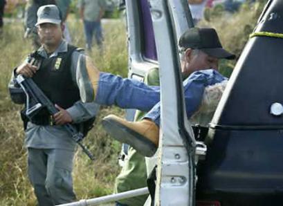 A coroner lifts one of six prison guards and workers who were found shot dead in a car outside Matamoros federal prison in northeastern Mexico, January 20, 2005. The murders are the latest in a string of murders and security breaches blamed on organized crime at Mexican federal prisons. (Kris Holland/Reuters) 