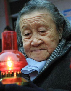 Li Xiuying, survivor of the Nanjing massacre in 1937 in which over 300,000 were killed by Japanese invaders, holds a red candle to commemorate the victims in Nanjing, East China's Jiangsu Province in this file photo. She died on December 4, 2004 before she won the defamation case against a right-wing Japanese writer. [newsphoto]