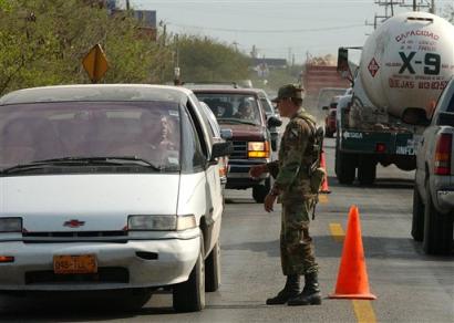 A soldiers checks vehicles near the entrance of a top security prison in the border city of Matamoros, northern Mexico on Friday Jan. 21, 2005. Drug traffickers were behind the slayings of six Mexican prison employees, specifically picking them out at a roadblock, officials said Friday, detailing the latest killings in an increasingly bloody turf war that has bodies turning up almost daily along the border. (AP Photo/Eduardo Verdugo) 