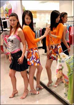 Models dressed in the items selected by shoppers to help them make up their minds pose by a mirror at a boutique in Beijing. China's booming economy grew even faster in 2004, expanding at a blistering pace of 9.5 percent after 9.3 percent the previous year, official statistics showed(AFP/File)