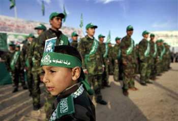 Palestinian youths of the Hamas movement participate in a rally in the northern Gaza Strip town of Beit Hanoun, Tuesday Jan. 25, 2005. Palestinian militant groups have agreed to suspend attacks at Israeli targets as they near a formal truce deal with Palestinian Authority President, Mahmoud Abbas, and await Israel's response moving the two sides closer to ending four years of bloody conflict. The photo on the boy's headband shows Salah Shehadeh, a Hamas commander that was killed in July 2002 with 14 others, when an Israeli plane dropped a one-ton bomb on his Gaza house. [AP] 