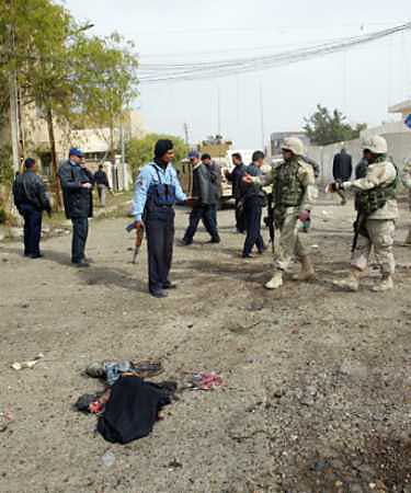 Iraqi police and U.S. Army soldiers examine the scene after a suicide bomber blew himself up near a polling station in Baghdad on January 30, 2005. At least 232 civilians have been killed while working on U.S.-funded contracts in Iraq and the death toll is rising rapidly, according to a U.S. government audit. [Reuters]