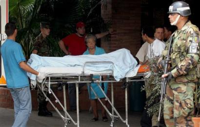 A wounded soldier is transferred to an ambulance to be taken to a hospital while another soldier stands guard in Cali, Colombia, 300 km (186 miles) southwest of Bogota, Tuesday, Feb. 1, 2005. Leftist rebels of the Revolutionary Armed Forces of Colombia, or FARC, attacked a Colombian Marine post in southwest Colombia with homemade rockets early this morning killing at least 14 soldiers and wounding about 25, the commander of the Colombian navy said. [AP]
