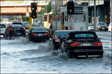 Commuters struggle through a flooded street after a night of fierce wind and heavy rain in Melbourne, 03 February 2005. Freak summer storms lashed eastern Australia overnight, dumping record rains on Melbourne, hitting Brisbane with a towering dust storm and killing a camping schoolgirl near Sydney, officials said. [Reuters]