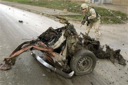 A U.S. Army 1st Battalion, 24th Infantry Regiment soldier examines the wreckage after a car bomb targeting his Army convoy exploded, causing minor injuries to two soldiers and six children in a nearby house in Mosul, Iraq Thursday, Feb. 3, 2005. Insurgents attacked U.S. and Iraqi troops throughout the day, also using small arms, mortars, rocket-propelled grenades and roadside bombs. [AP]