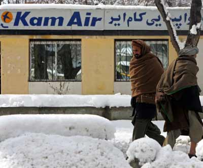 Afghans walk past the office of the private airline Kam Air in Kabul February 4, 2005. An Afghan passenger plane missing since Thursday with 104 people on board, including at least 13 foreginers, may have crashed after being turned away from Kabul airport during a snow storm, officials said on Friday. [Reuters]
