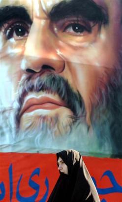 An Iranian woman, stands in front of a picture of the late revolutionary founder, Ayatollah Khomeini, during a ceremony marking the 26th anniversary of the Islamic Revolution's victory, at the Behesht-e-Zahra cemetery, just outside Tehran, Iran, Thursday, Feb. 3, 2005. (AP Photo/Vahid Salemi) 