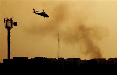 A U.S. military helicopter hovers over the scene of a mortar attack near the airport on Baghdad's western outskirts in Iraq Saturday, Feb. 5, 2005. [AP]