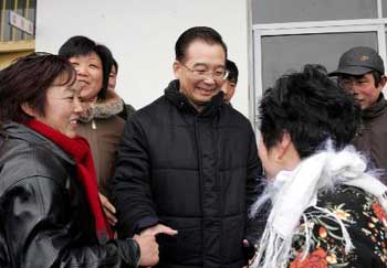 Chinese Premier Wen Jiabao (center) extends to shake hands with an AIDS patent (back to camera) on the eve of the Chinese lunar new year in a village in Shangcai, Central China's Henan Province February 8, 2005. [Xinhua]