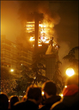 People watch as Windsor building burns in downtown Madrid. Squadrons of firefighters battled a huge blaze which broke out at the office block in central Madrid, spreading through several floors and forcing the evacuation of dozens of families living nearby(AFP/Javier Soriano) 