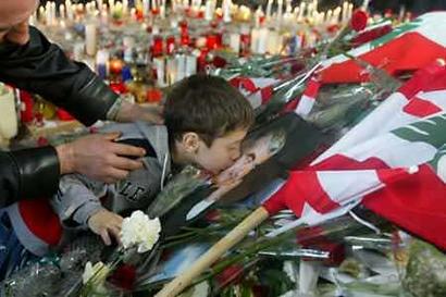 A Lebanese child is held by his father as he kisses a picture of assassinated former prime minister Rafik al-Hariri among a mountain of wreathes covering the grave in Beirut, February, 20, 2005. Thousands of Lebanese residents visit Hariri's grave in downtown Beirut daily since he was buried on Wednesday in a funeral that turned into an outpouring of anger against Syria, which many blame for his killing in a huge car bomb. Photo by Jamal Saidi/Reuters