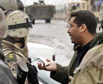 An Iraqi man shows his identification card to Iraqi Intervention Force Soldiers, who are conducting a cordon and search operation in the northern city of Mosul, in this photograph handed out on February 23, 2005. A suspected suicide car bomber blew up his vehicle at a police station in the northern Iraq city of Tikrit on Thursday, killing at least 10 people and wounding 25, police and hospital officials said. [Reuters]